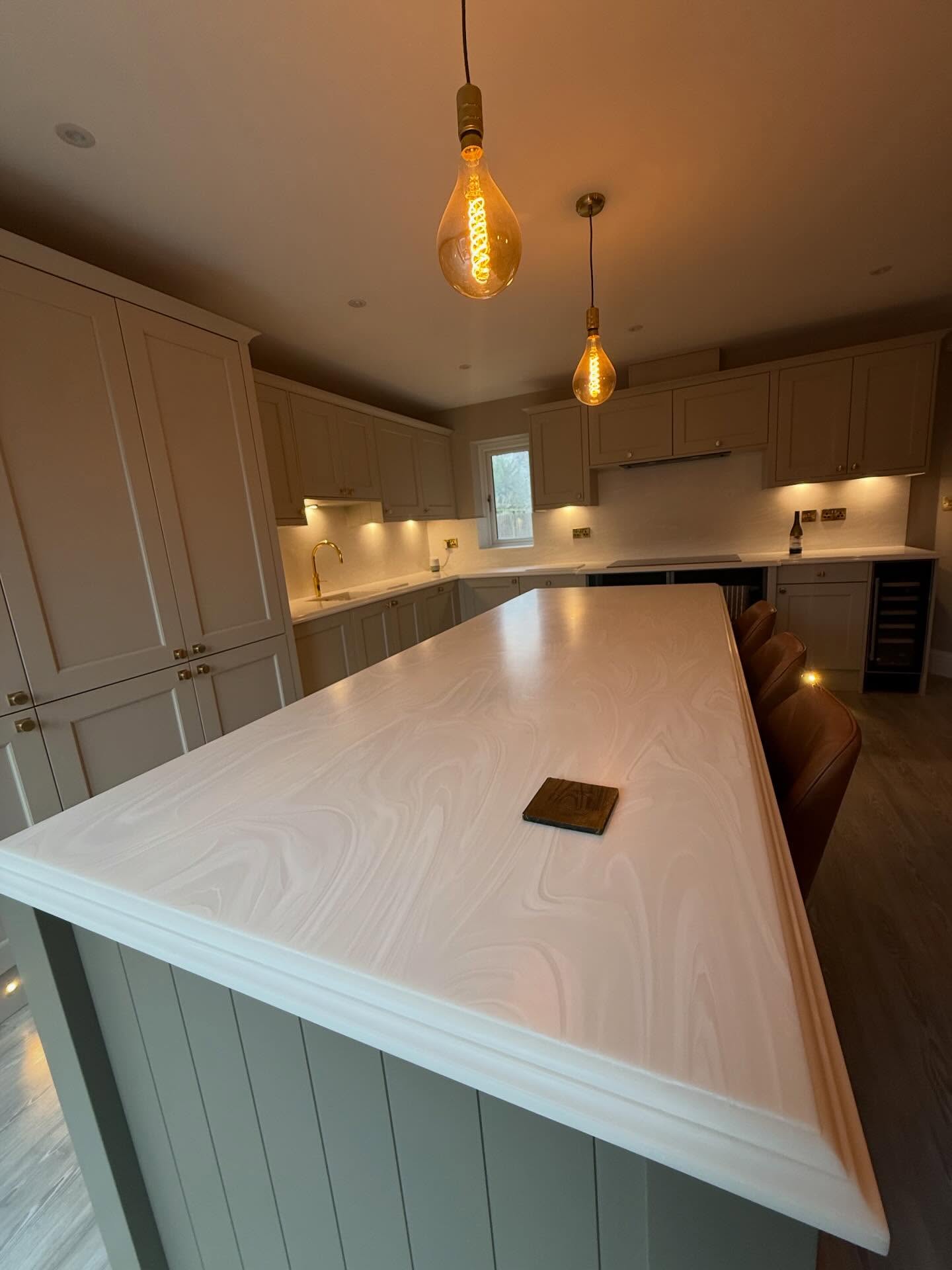 Finished cream shaker kitchen with a panelled island under pendant bulbs