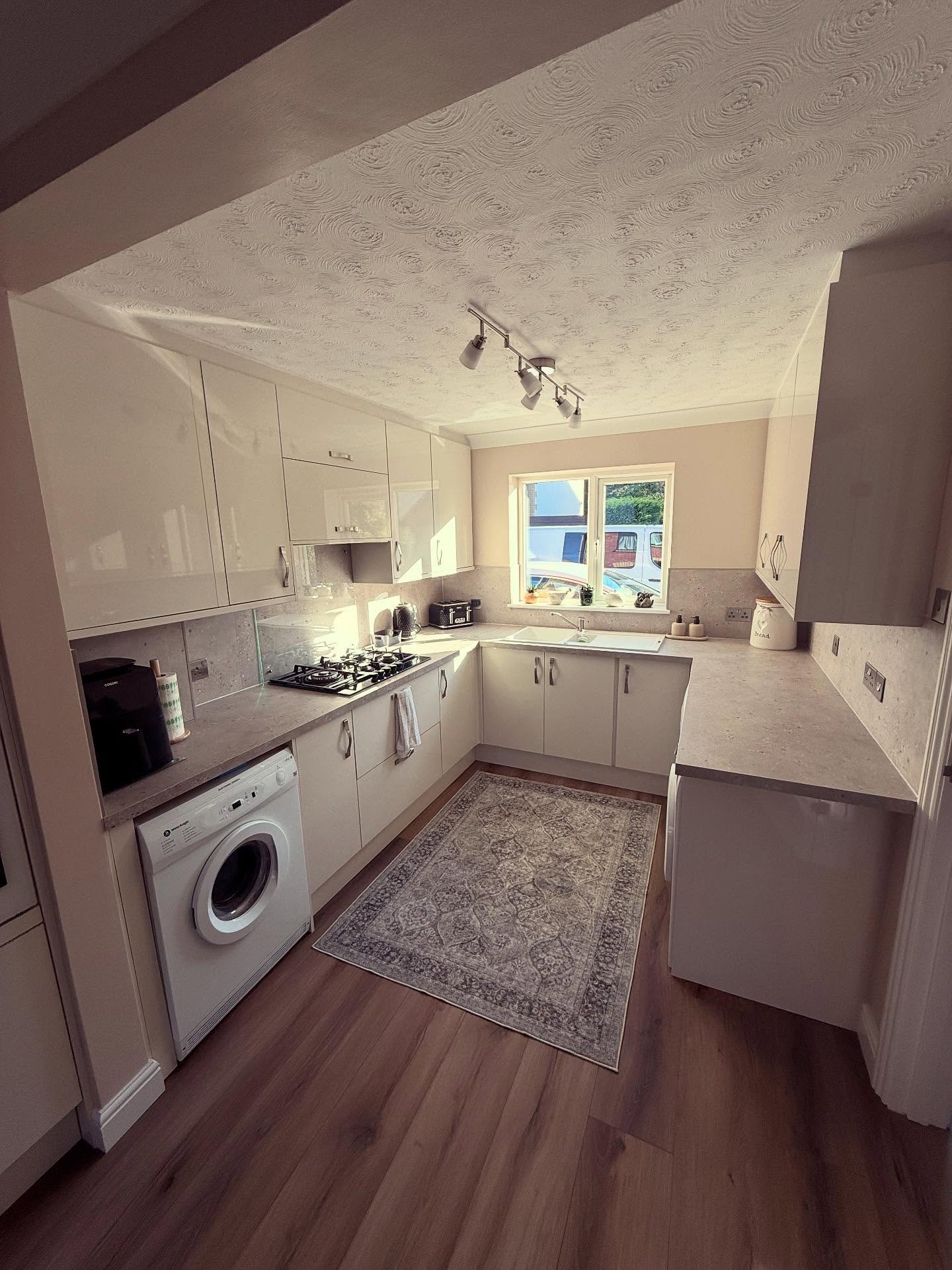 Cream gloss Howdens galley kitchen with a wood-effect floor